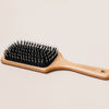 NATULIQUE Professional Paddle Brush with wooden handle and bristles for effective styling and smoothing hair.