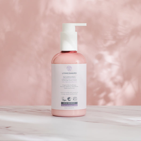 LYKKEGAARD Nourishing Softening Hand Cream bottle on pink background, featuring organic ingredients for deep hydration.
