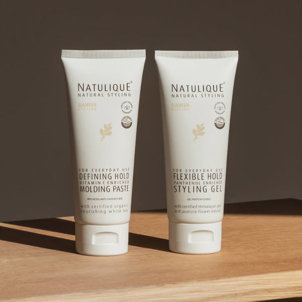 NATULIQUE styling products, 98% organic, defining hold molding paste and flexible hold gel on a wooden surface.