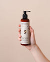 NATULIQUE BioActive Bond Strengthening Conditioner bottle held in hand, designed for deep hair repair and nourishment.