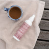 NATURIGIN Define and Reshape Wake Up Curl Spray next to a cup of coffee on a towel, perfect for revitalizing curls.