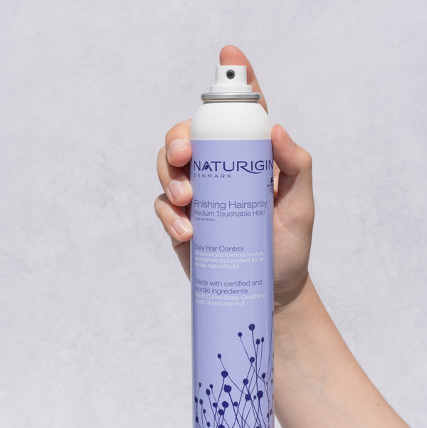 NATURIGIN Medium Hold Finishing Hairspray in hand, designed for flexible hold and organic nourishment for healthy hair.