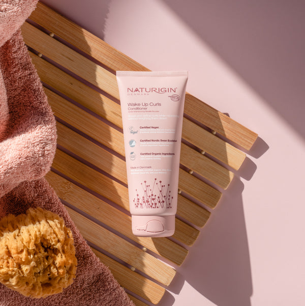NATURIGIN Wake Up Curls Conditioner on a wooden surface, designed for soft, defined, frizz-free curls.