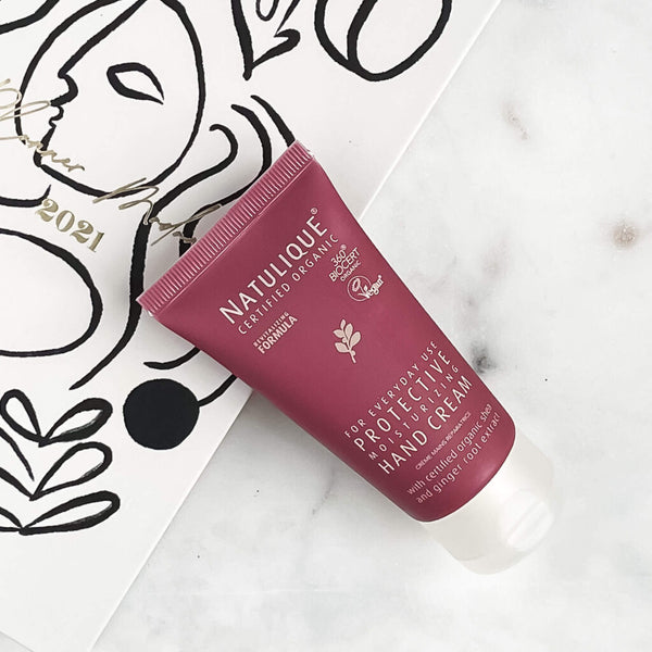 NATULIQUE Organic Protective Hand Cream tube on a stylish background for luxurious hydration and natural skin care.