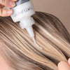 Applying NATURIGIN ammonia-free light ash brown hair color to hair for a cool, sophisticated look.