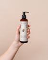 NATULIQUE Organic BioActive Bond Strengthening Shampoo in a hand, designed to revive and protect damaged hair.