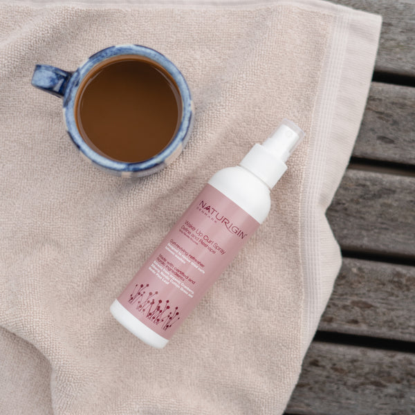 NATURIGIN Define and Reshape Wake Up Curl Spray next to a cup of coffee on a towel, perfect for revitalizing curls.