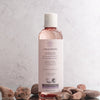 LYKKEGAARD Hydrating Multipurpose Body Oil in a clear bottle, surrounded by smooth stones, ideal for radiant skin.